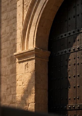 Sunlit stone archway with a heavy wooden gate